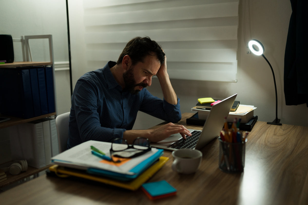 A stressed man working late at night on his laptop, the night before a deadline