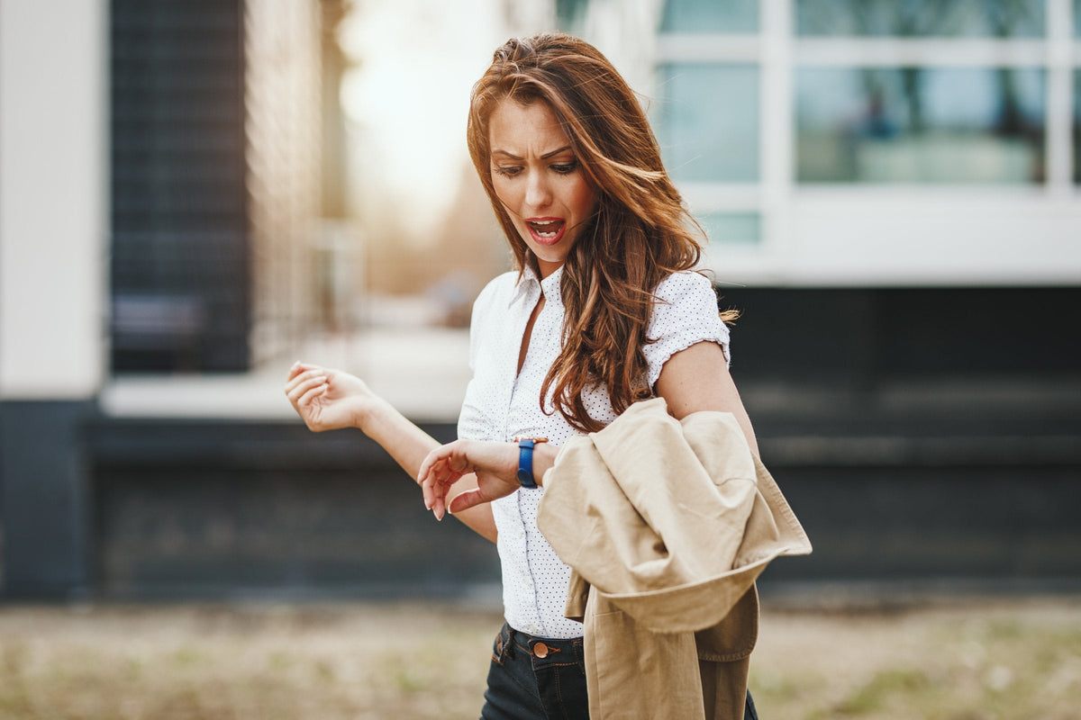 A worried young woman looking at her watch, realizing she's running late
